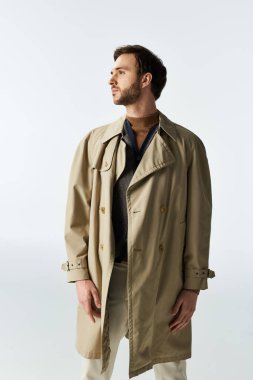 Şık trençkotlu kendine güvenen bir beyefendi modern moda sergiliyor..