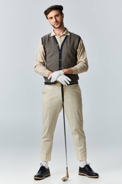 Yakışıklı bir adam şık giyinmiş, dengeli duruyor. Şık giyinmiş, golfe hazır..