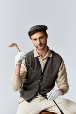 Yakışıklı, iyi giyimli bir adam elinde golf sopası tutarken evin içinde kendine güveni ve cazibesi yayılıyor..