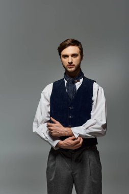 Seçkin bir yelek ve pantolon giymiş, şık bir züppe duruşu olan.
