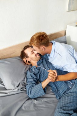 A joyful gay couple share a tender moment in their pajamas, basking in the warmth of a sunny morning. clipart