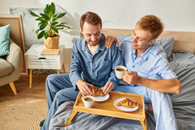 İki erkek birlikte güzel bir sabah geçirir, pijamalarıyla kahvaltı eder ve neşeyle kahveyi yudumlarlar..