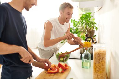 Sevgi dolu bir çift, parlak mutfaklarında taze bir salata hazırlarken kahkaha ve yemek pişirme tutkusunu paylaşır..