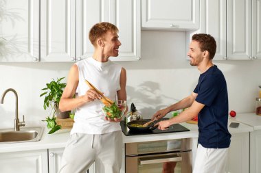 A loving couple happily cooks in their contemporary kitchen, sharing joy while making a fresh meal. clipart