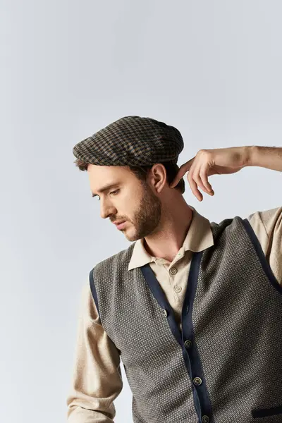 stock image A dapper gent in a classic ensemble thoughtfully adjusts his cap with a contemplative expression.