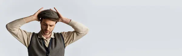 stock image A dapper young man reflects while adjusting his fashionable hat, exuding charm and elegance.