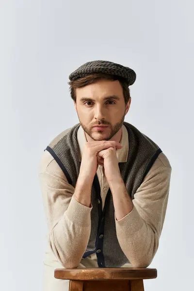 stock image A handsome man in a stylish outfit rests his chin on his hands, reflecting thoughtfully.