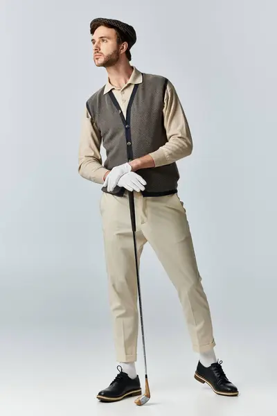 stock image The dandy stands elegantly with a golf club, embodying classic style and sophistication.