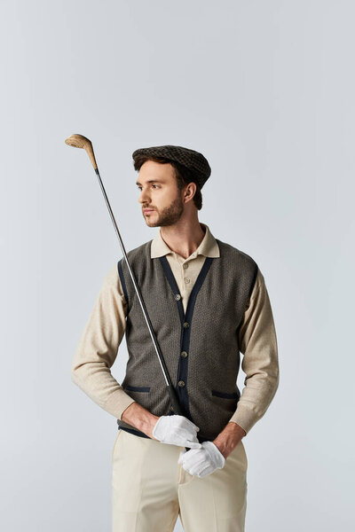 Одетый в винтажный костюм для гольфа, он уверенно позирует с клюшкой для гольфа в руке..