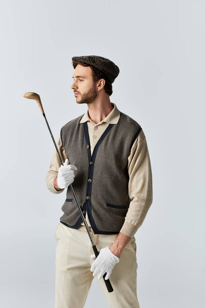 The well dressed individual stands gracefully holding a golf club, showcasing his elegant style.
