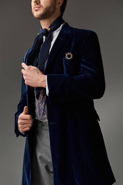 Красивый мужчина, одетый в бархатное пальто и шарф источает очарование и изысканность в помещении.