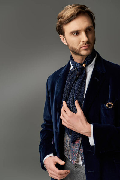 Хорошо одетый мужчина в стильном наряде вдумчиво настраивает свой шарф, источая элегантность и очарование..