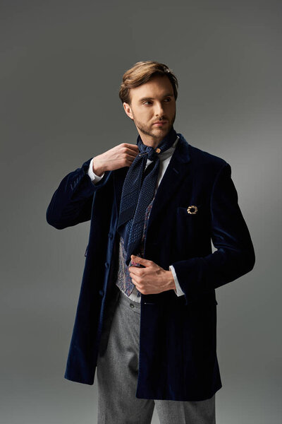 Стильный мужчина настраивает свой шарф, излучая элегантность в изысканном наряде.