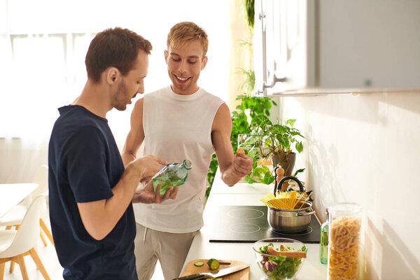 A loving couple shares a delightful moment as they chop vegetables and create a vibrant salad in their kitchen.