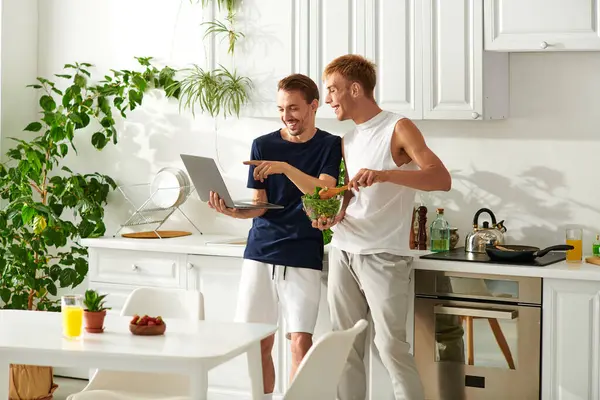 stock image In a bright kitchen, a happy couple engages in cooking as watching video and enjoy each others company.