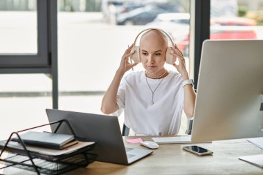 A young bald woman is engrossed in her work at a modern desk, wearing elegant attire and headphones. clipart