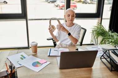 A young bald woman in stylish attire prepares for a virtual conference, focused and poised. clipart