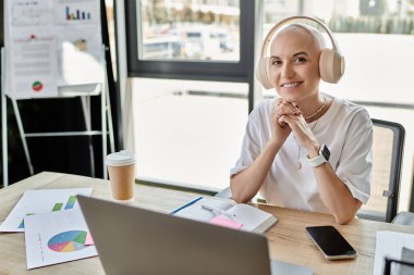 A young bald woman in stylish clothing interacts with technology, exuding confidence. clipart