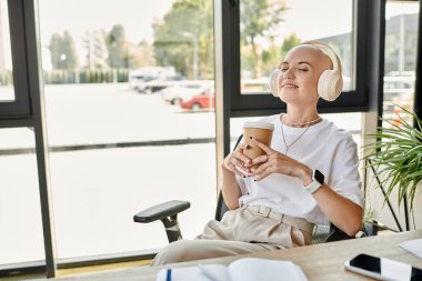 A young bald woman enjoys a drink, savoring tranquility in a chic environment. clipart