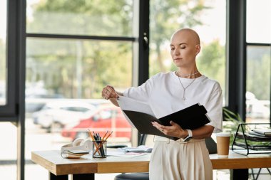 Zarif bir şekilde giyinmiş genç kel bir kadın parlak ofis alanındaki önemli belgeleri inceliyor..