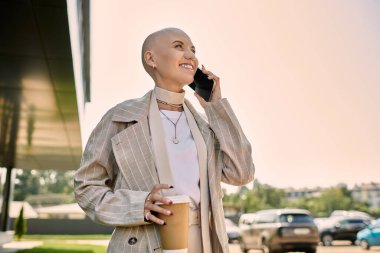 Şık giyinmiş, kel bir kadın dışarıdaki bir telefon görüşmesinden zevk alıyor. Kendine güveni ve neşesi tam..