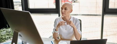 A young bald woman in stylish clothing sits at her desk, deep in contemplation, engaged in work. clipart