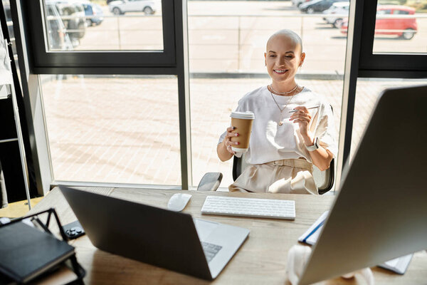 Молодая женщина тепло улыбается с кофе в руке в своем стильном офисе в солнечный день.