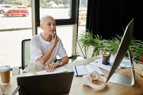 stock image A stylish bald woman immerses herself in work, thoughtfully handling tasks at her desk.