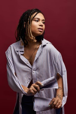 Saçları örgülü şık bir genç kadın tarzını cesur bir arka plana karşı sergiliyor, kendine güveni ve yeteneği tam..