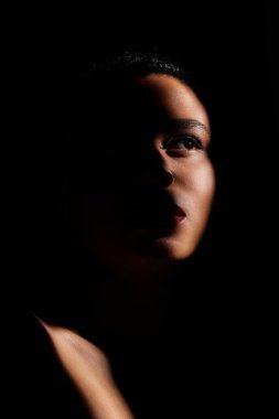 A young African American woman with striking red lips in a dimly lit studio. clipart