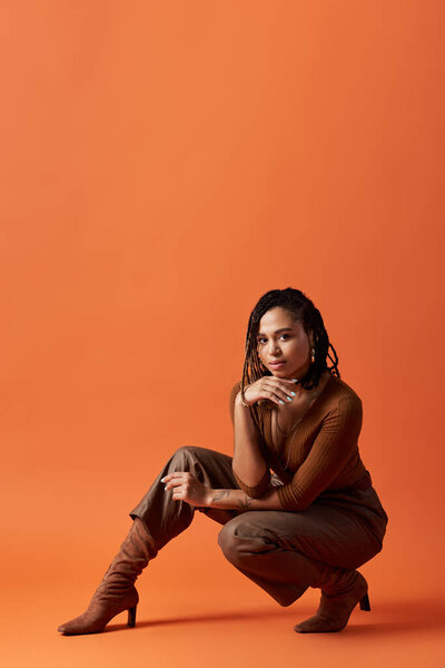A fashion-forward African American woman showcases her style with braided hair in an artistic studio atmosphere.