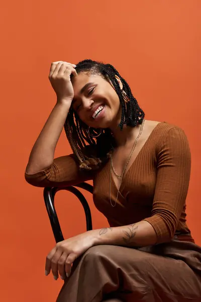 stock image A young African American woman with braided hair smiles joyfully while posing in a colorful studio atmosphere.