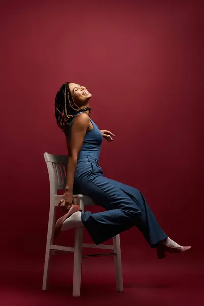 stock image A young African American woman with braided hair exudes confidence while playfully posing in a studio setting.