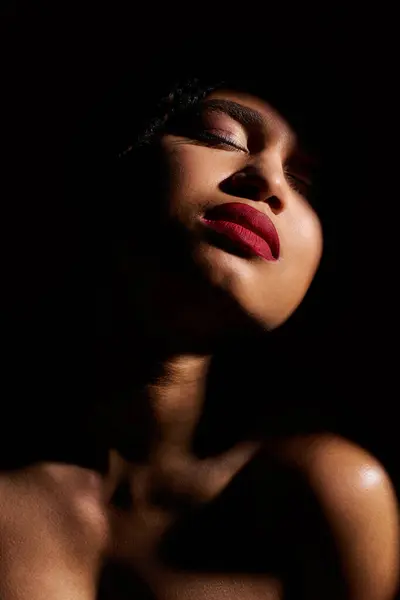 stock image A fashionable African American woman showcases her radiant style with striking red lips in a studio.