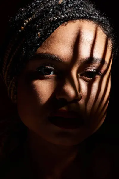 stock image A young African American woman with braided hair and red lips showcases her style in a captivating studio atmosphere.