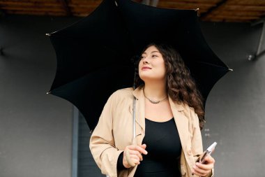 Soğuk bir sonbahar gününde, genç ve iri yarı bir kadın açık havada şık siyah ve bej elbiseler giyer..