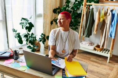 The young woman smiles as she arranges colorful papers in her plant filled home workspace. clipart