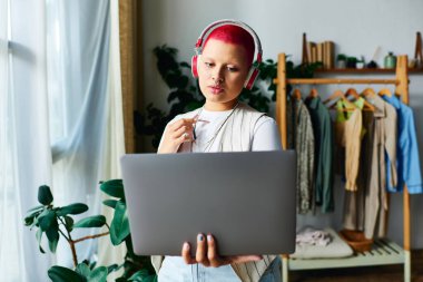 Canlı saçlı genç bir kadın sıcak evinden online bir toplantıya dikkatle katılıyor..
