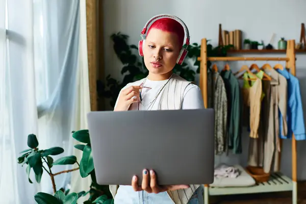 stock image A young woman with vibrant hair attentively participates in an online meeting from her cozy home.