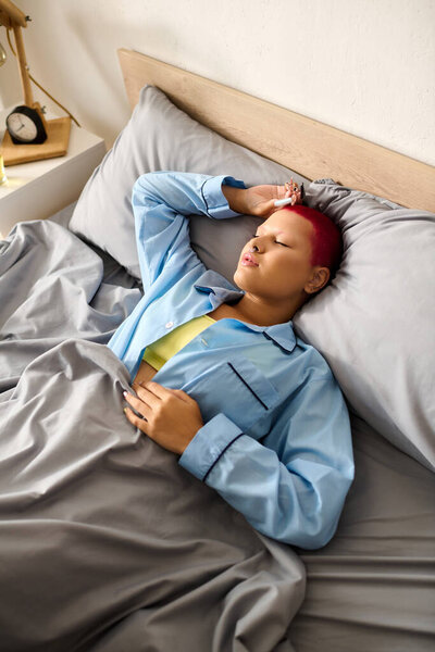 The woman enjoys a tranquil morning at home, laying comfortably in bed with a soft blanket.