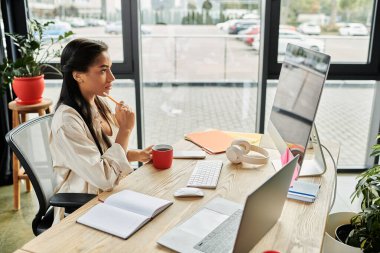 Genç bir kadın şık bir ofis masasında çalışırken özenle içkisini yudumluyor..
