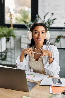 A young beautiful woman smiles warmly while working at her desk, surrounded by greenery. clipart