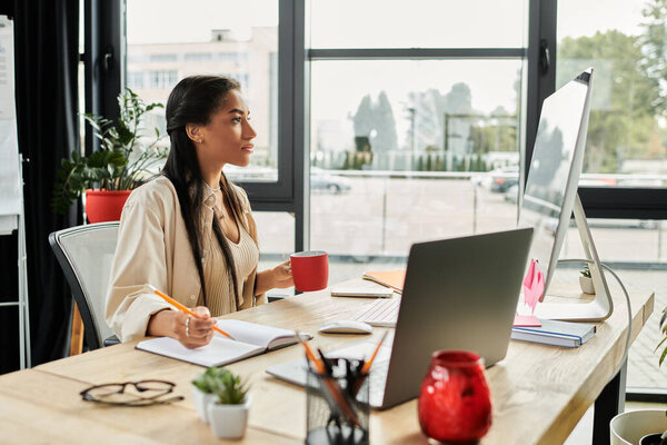 A focused young woman sits at her desk, sipping coffee while brainstorming ideas for her work.