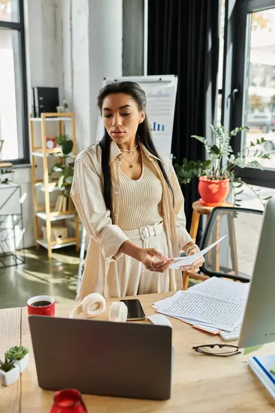 stock image The young woman focuses intently on her work at her bright, stylish office table.