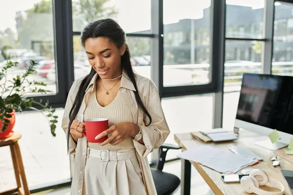 Stock image A beautiful woman enjoys a warm drink in her sunlit, stylish office.