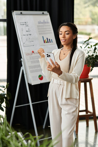 Уверенная в себе молодая женщина в профессиональной одежде взаимодействует со своим смартфоном, представляя данные.