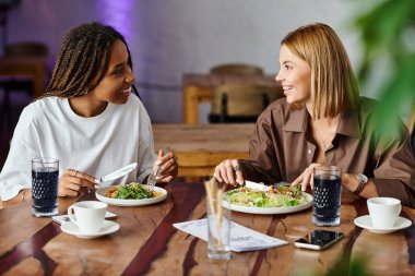 İki kadın, hoş bir kafede lezzetli bir yemek yerken keyifli bir sohbetten hoşlanırlar..