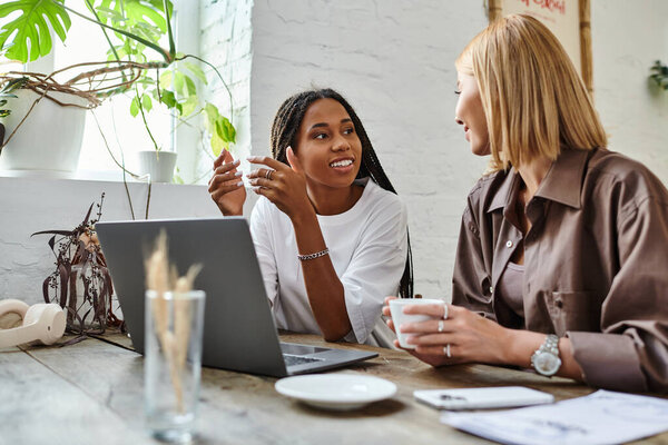 Радостный момент разворачивается, когда женщина улыбается своей девушке, пока они пьют кофе в кафе