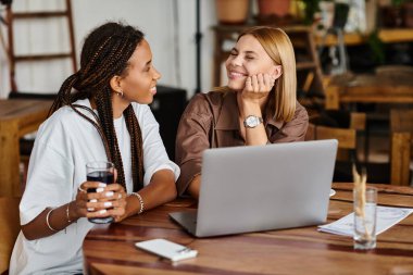 İki kadın bir kafede birlikte olmaktan zevk alıyor, içkilerini paylaşırken kahkaha ve sevgi dolu..