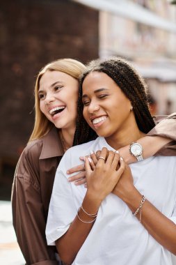 An African American woman with braided hair smiles warmly at her girlfriend clipart